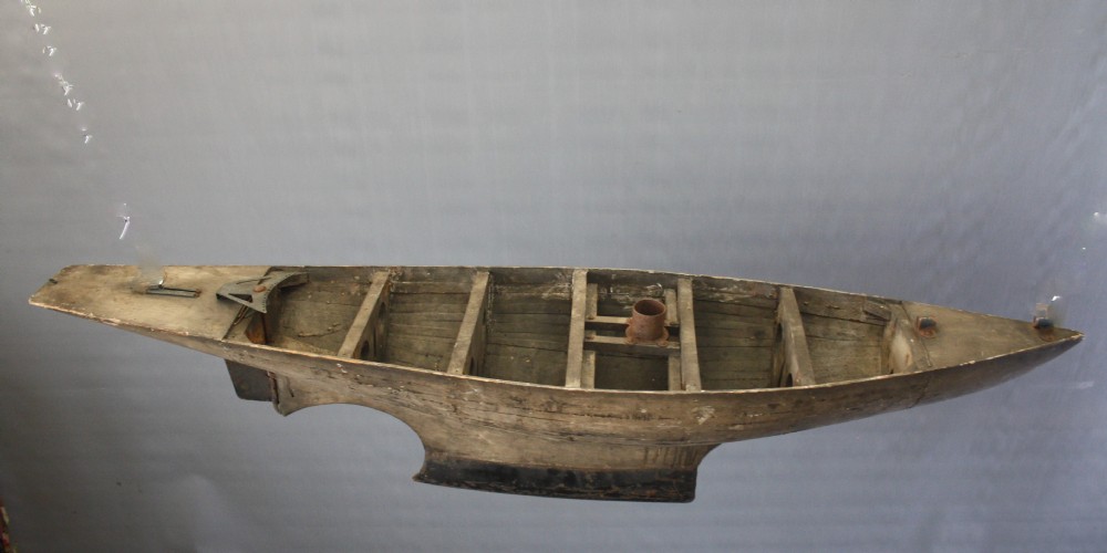 A large carved wooden pond yacht hull featuring exposed interior deck ribs and a weighted metal keel. View VII