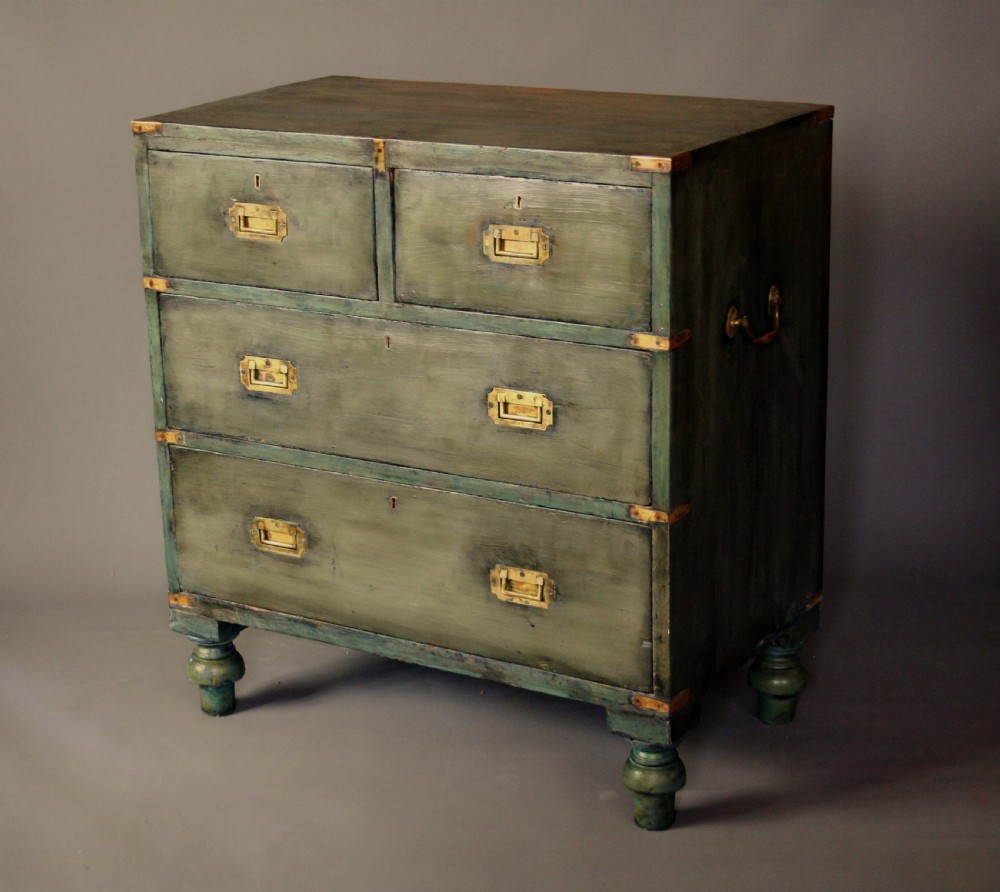 A Victorian green painted campaign chest of drawers with flush brass corner mountings, recessed brass handles, side carrying handles, and turned feet.