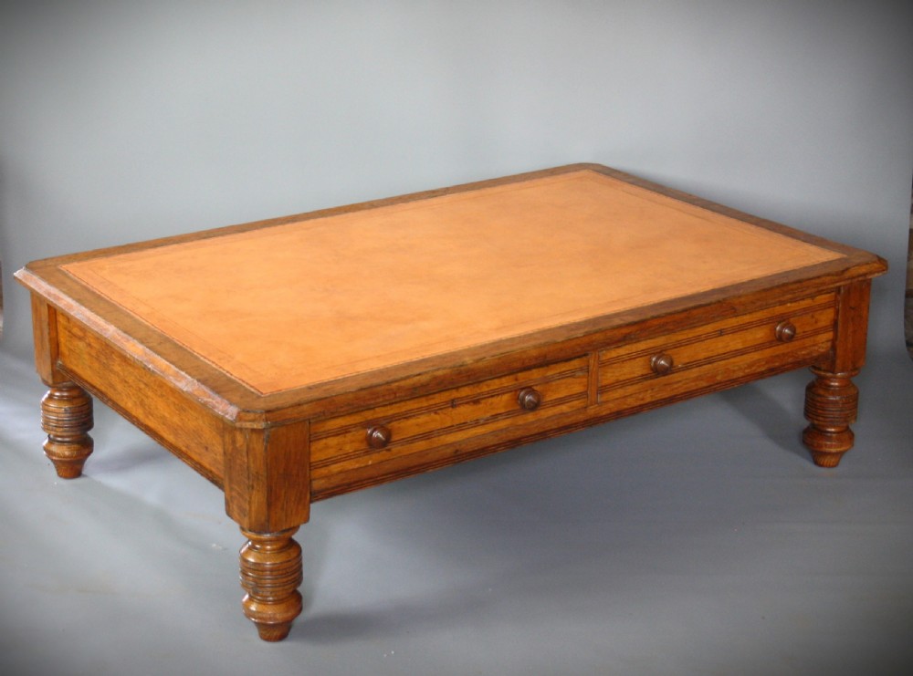 A low rectangular golden oak coffee table featuring a leather inset top, two front drawers with turned wooden knobs, and stout turned legs. View III