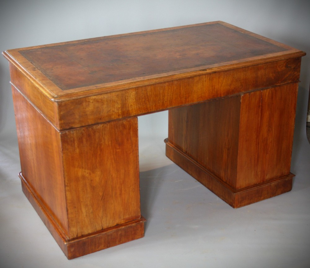 An antique Victorian walnut pedestal desk featuring nine drawers with turned wooden knobs and a leather inset writing surface. View IV