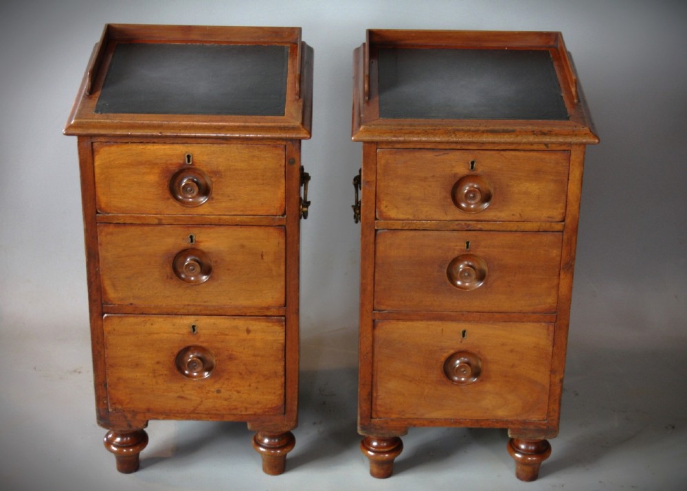 A pair of antique brown wooden military campaign bedside cabinets featuring three drawers each, brass side handles, and black leather tops. View II