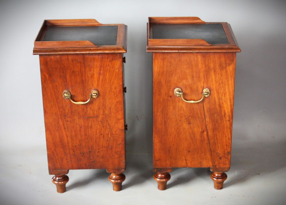 A pair of antique brown wooden military campaign bedside cabinets featuring three drawers each, brass side handles, and black leather tops. View V