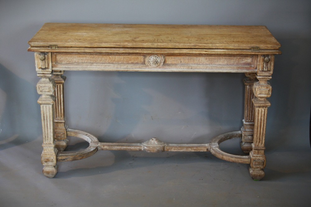 An antique light oak metamorphic console table featuring fluted square legs, a central carved rosette on the apron, a curved stretcher, and a hinged fold-over top. View III