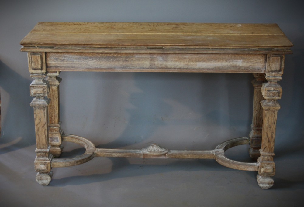 An antique light oak metamorphic console table featuring fluted square legs, a central carved rosette on the apron, a curved stretcher, and a hinged fold-over top. View VI