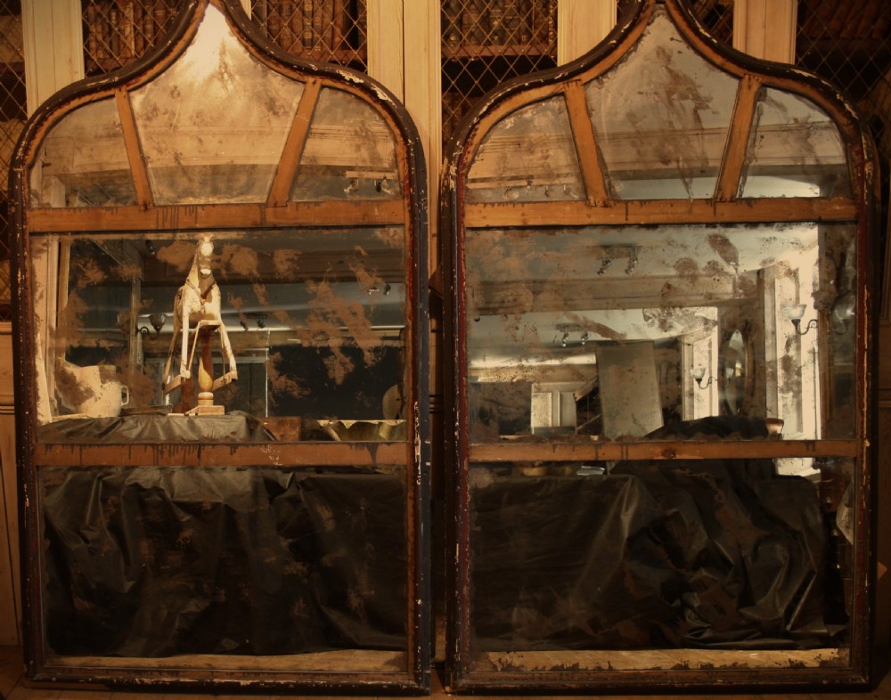 A pair of large Gothic Revival wall mirrors featuring pointed arched wooden frames with dark distressed paint and paneled mirror glass with foxing. View II