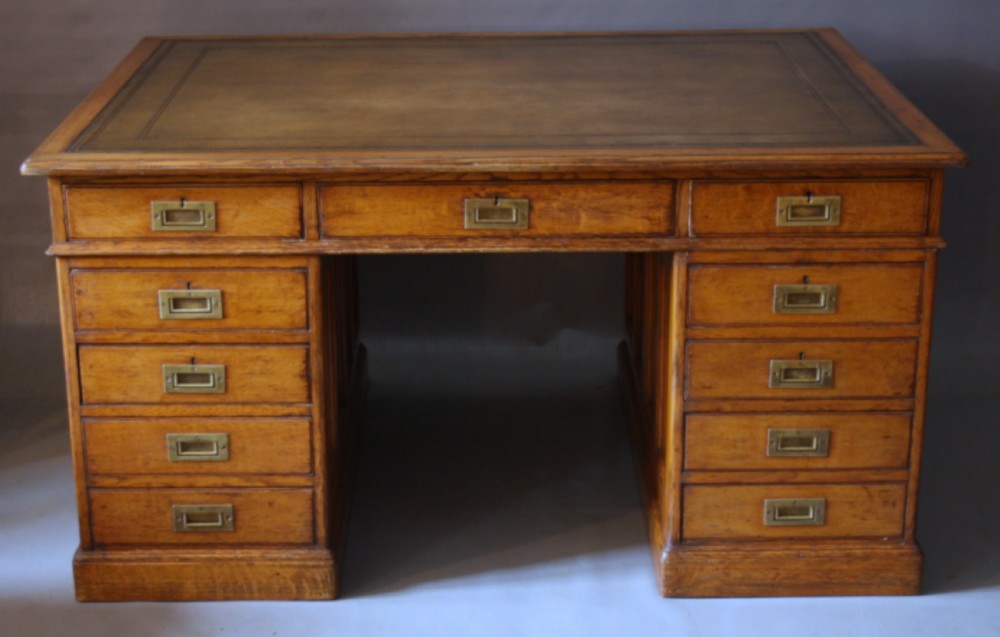 A large Victorian oak partners desk featuring a brown leather inset writing surface, nine front drawers with brass handles, and panelled sides. View II