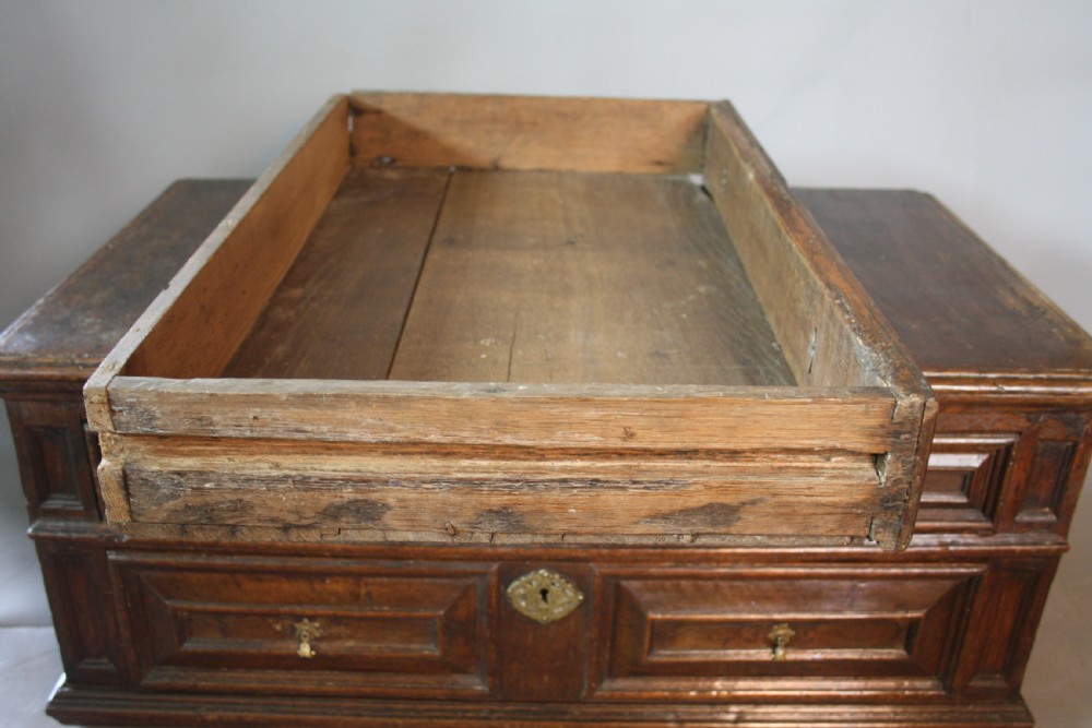 A late 17th-century dark oak chest of drawers featuring four drawers decorated with geometric mitred mouldings and brass keyhole escutcheons. View IX