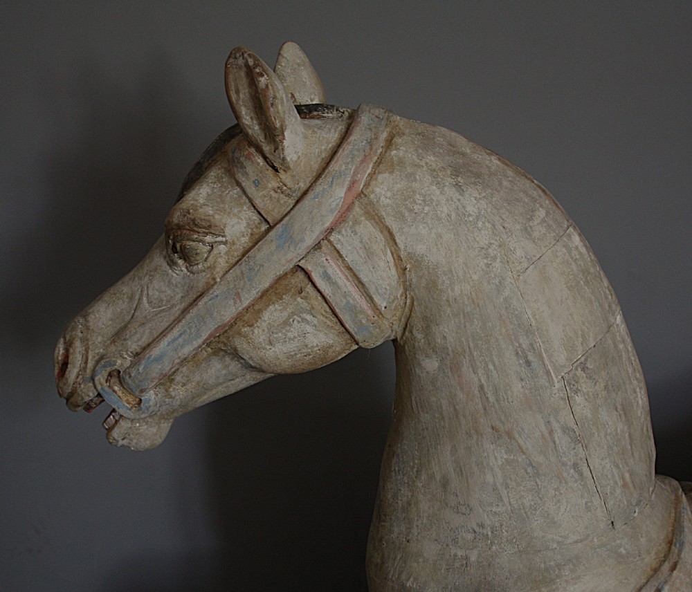 A carved wooden early 20th-century carousel horse with distressed off-white paint and dark details, displayed on a twisted iron mount. View III