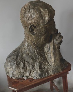 A patinated dark brown plaster bust depicting a male cellist holding a cello scroll, sculpted with a heavy, impasto-like textured finish. View II