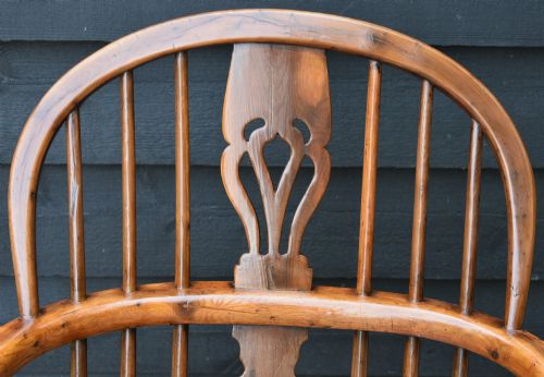 fig 1. A 19th-century English Windsor armchair made from yew and elm wood featuring a hoop back, a central pierced splat, turned legs, and a crinoline stretcher.
