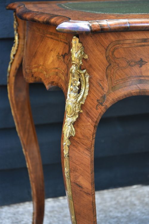 A nineteenth-century French kingwood writing desk featuring a serpentine top, marquetry inlay, slender cabriole legs, and ornate gilt bronze mounts. View II