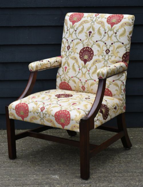 fig 1. A Georgian Gainsborough armchair featuring a dark mahogany frame with curved arm supports, upholstered in cream fabric with red and green botanical patterns.