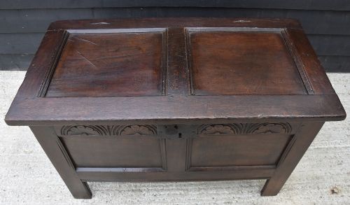 A dark 17th-century oak coffer featuring a carved lunette frieze, twin-panel front, hinged lid, and central iron escutcheon. View VI