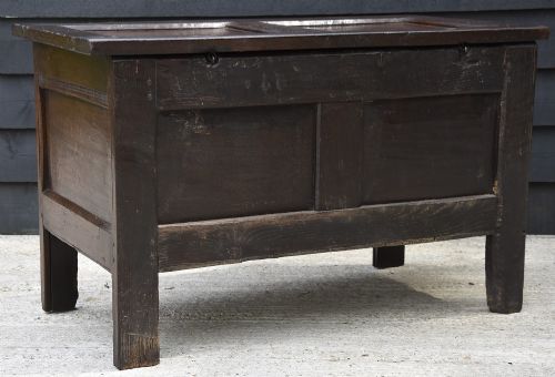A dark 17th-century oak coffer featuring a carved lunette frieze, twin-panel front, hinged lid, and central iron escutcheon. View IX