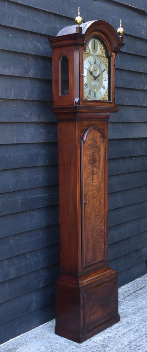 fig 1. An 18th-century Georgian longcase clock in flame mahogany with an arched brass dial and brass finials.