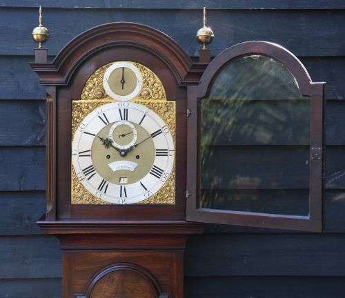 fig 2. An 18th-century Georgian longcase clock in flame mahogany with an arched brass dial and brass finials.