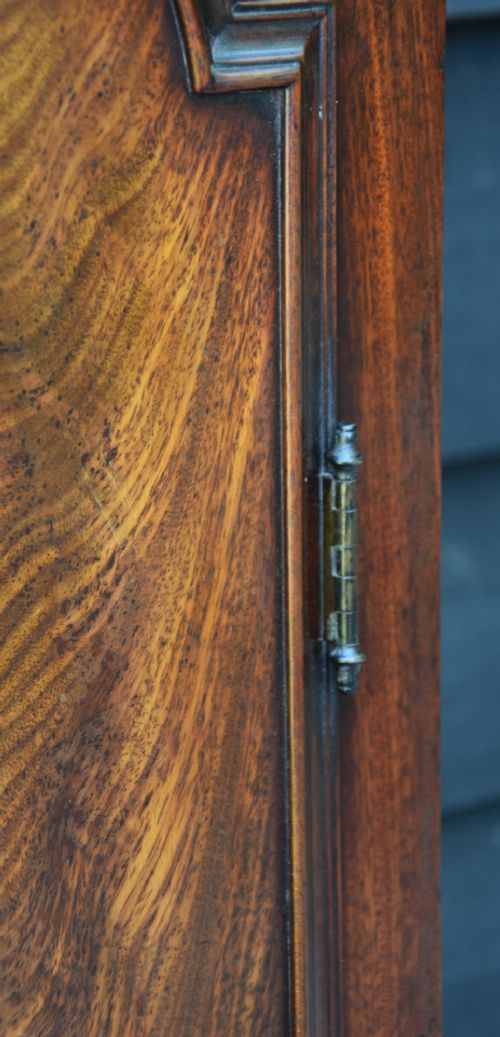 An 18th-century Georgian longcase clock in flame mahogany with an arched brass dial and brass finials. View VIII