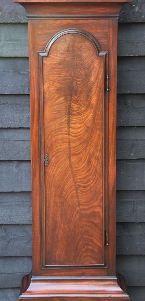 An 18th-century Georgian longcase clock in flame mahogany with an arched brass dial and brass finials. View XII