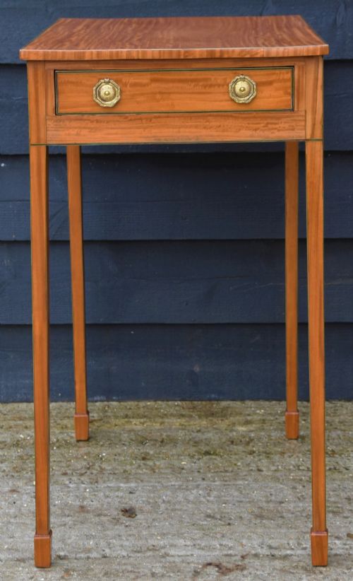 fig 1. A Georgian satinwood lamp table featuring a single frieze drawer with brass handles and slender square tapered legs.