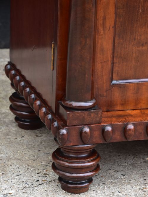 fig 1. A Regency mahogany chiffonier cabinet featuring an ornate carved shell crest shelf, frieze drawer, two cupboard doors with flame mahogany panels, and turned feet.