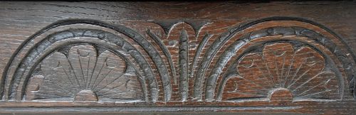 A dark oak coffer from the 17th century featuring twin front panels, carved lunette motifs across the frieze, an iron keyhole plate, and upright stile legs. View VII