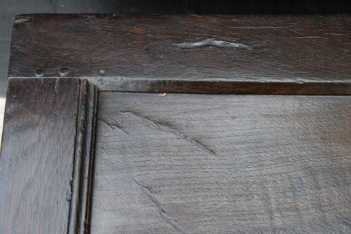 A dark oak coffer from the 17th century featuring twin front panels, carved lunette motifs across the frieze, an iron keyhole plate, and upright stile legs. View VIII