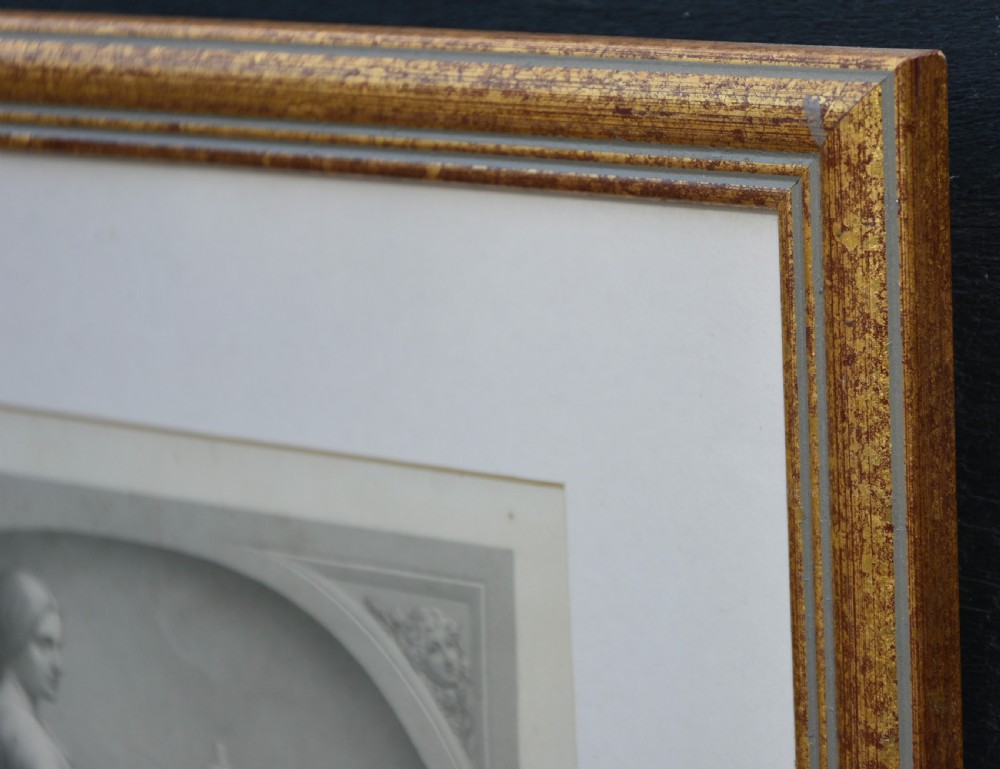 A framed nineteenth-century monochrome engraving depicting a seated woman in draped classical attire inside an arched niche, presented in a gold gilt frame. View III