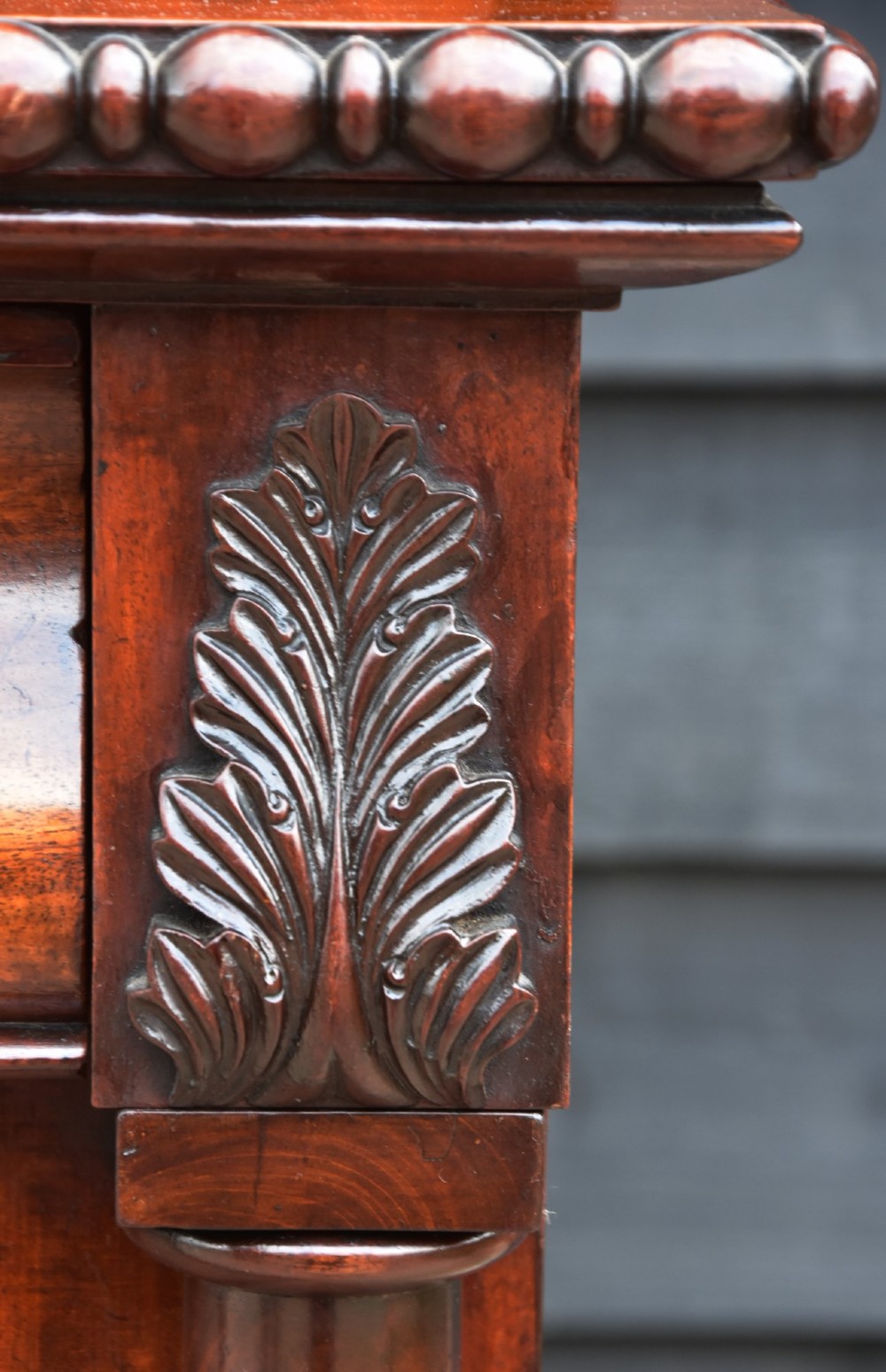 A Regency mahogany chiffonier side cabinet featuring a carved cresting gallery shelf, flame mahogany cupboard doors, and turned feet. View IV