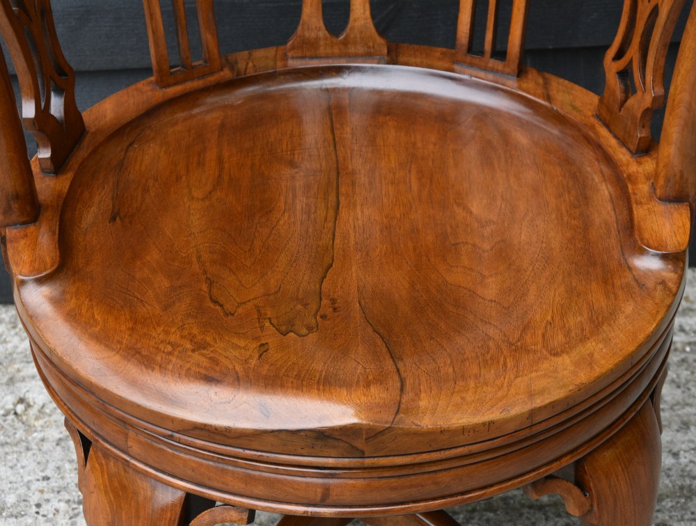 A late 19th-century Gothic Revival carved walnut revolving desk chair featuring an arched backrest with open tracery, curved armrests, a circular seat, and cabriole legs with an X-stretcher. View III
