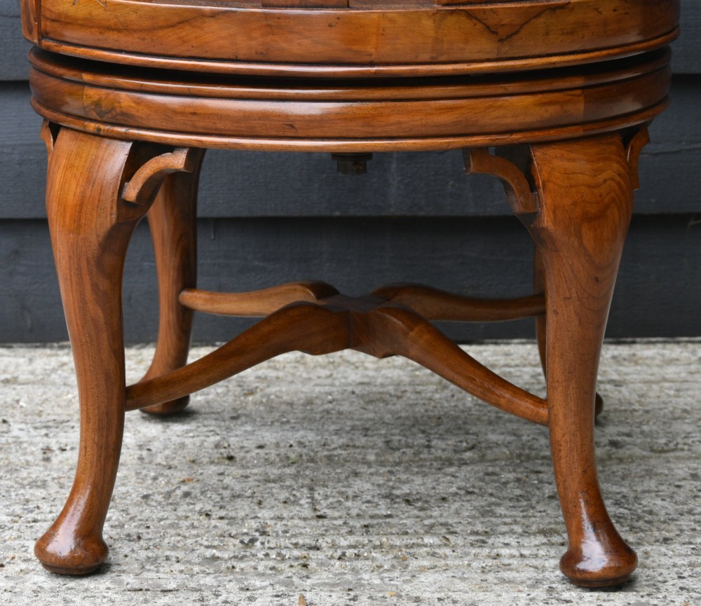 A late 19th-century Gothic Revival carved walnut revolving desk chair featuring an arched backrest with open tracery, curved armrests, a circular seat, and cabriole legs with an X-stretcher. View VI