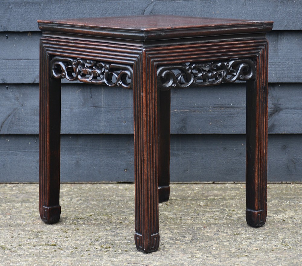 A dark rosewood square low table featuring a framed panel top, openwork carved aprons, and reeded legs. View II