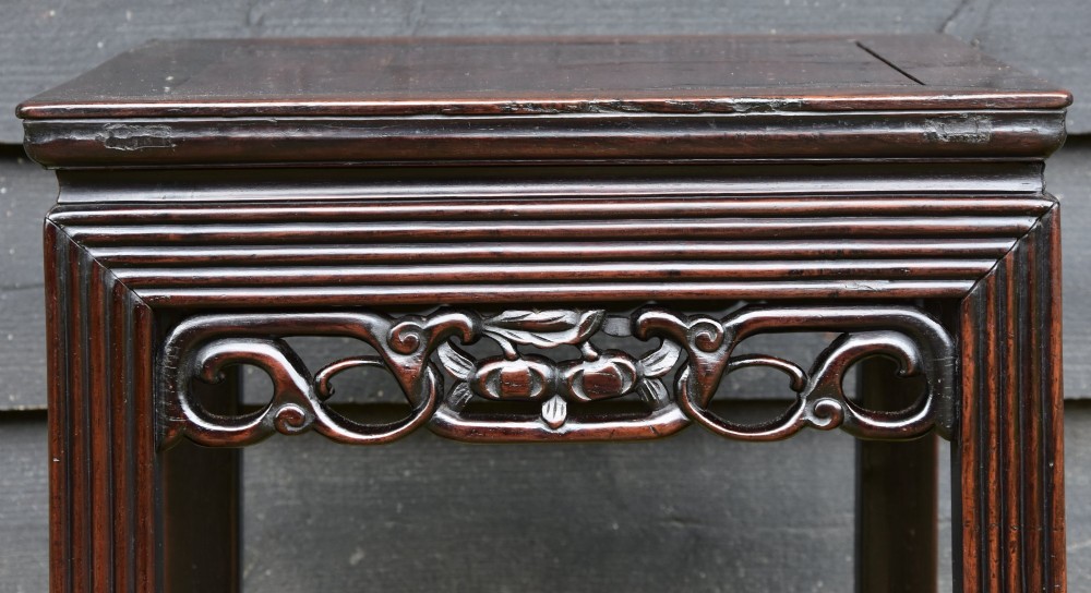 A dark rosewood square low table featuring a framed panel top, openwork carved aprons, and reeded legs. View III
