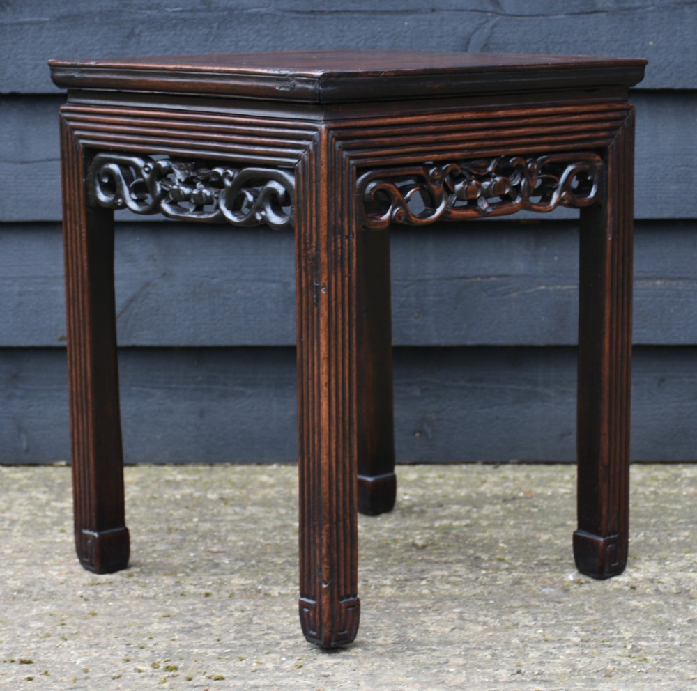 A dark rosewood square low table featuring a framed panel top, openwork carved aprons, and reeded legs. View VI