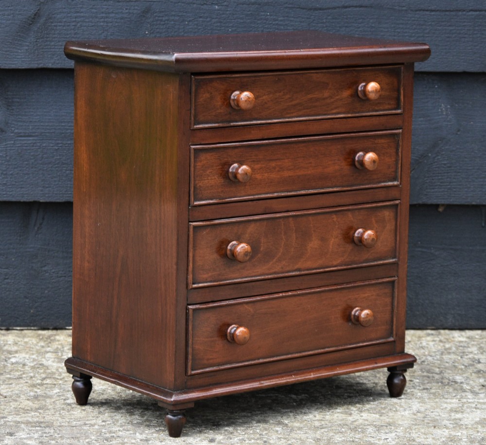 A Victorian mahogany miniature chest of drawers with four graduated drawers, turned wooden knobs, and turned feet. View III