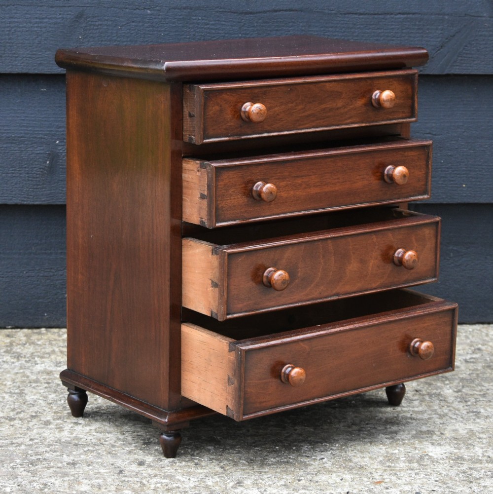 A Victorian mahogany miniature chest of drawers with four graduated drawers, turned wooden knobs, and turned feet. View V