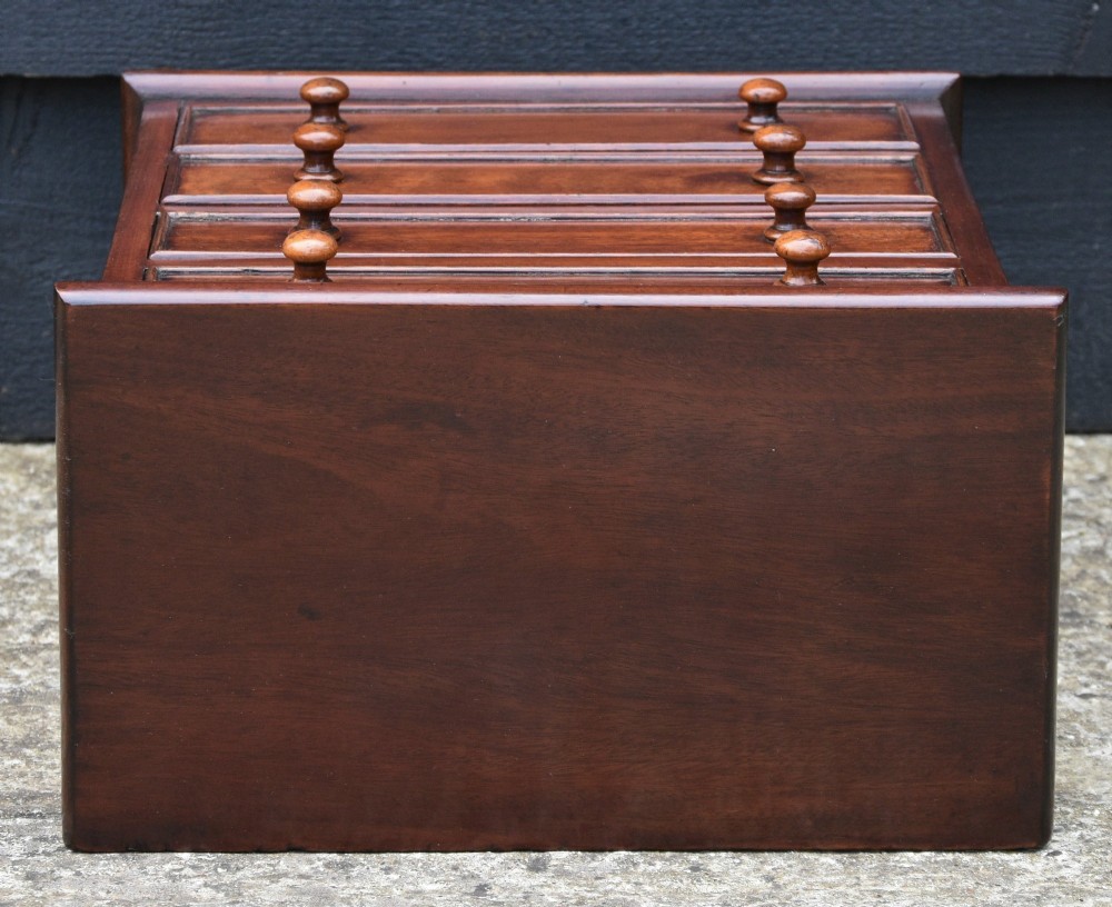 A Victorian mahogany miniature chest of drawers with four graduated drawers, turned wooden knobs, and turned feet. View VI