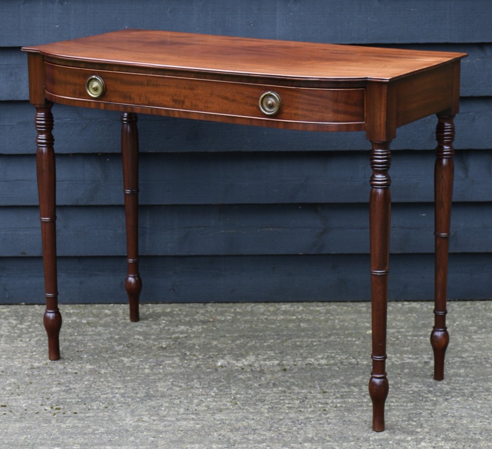 A Regency mahogany bow-fronted side table featuring a central drawer with circular brass handles and slender turned legs. View III
