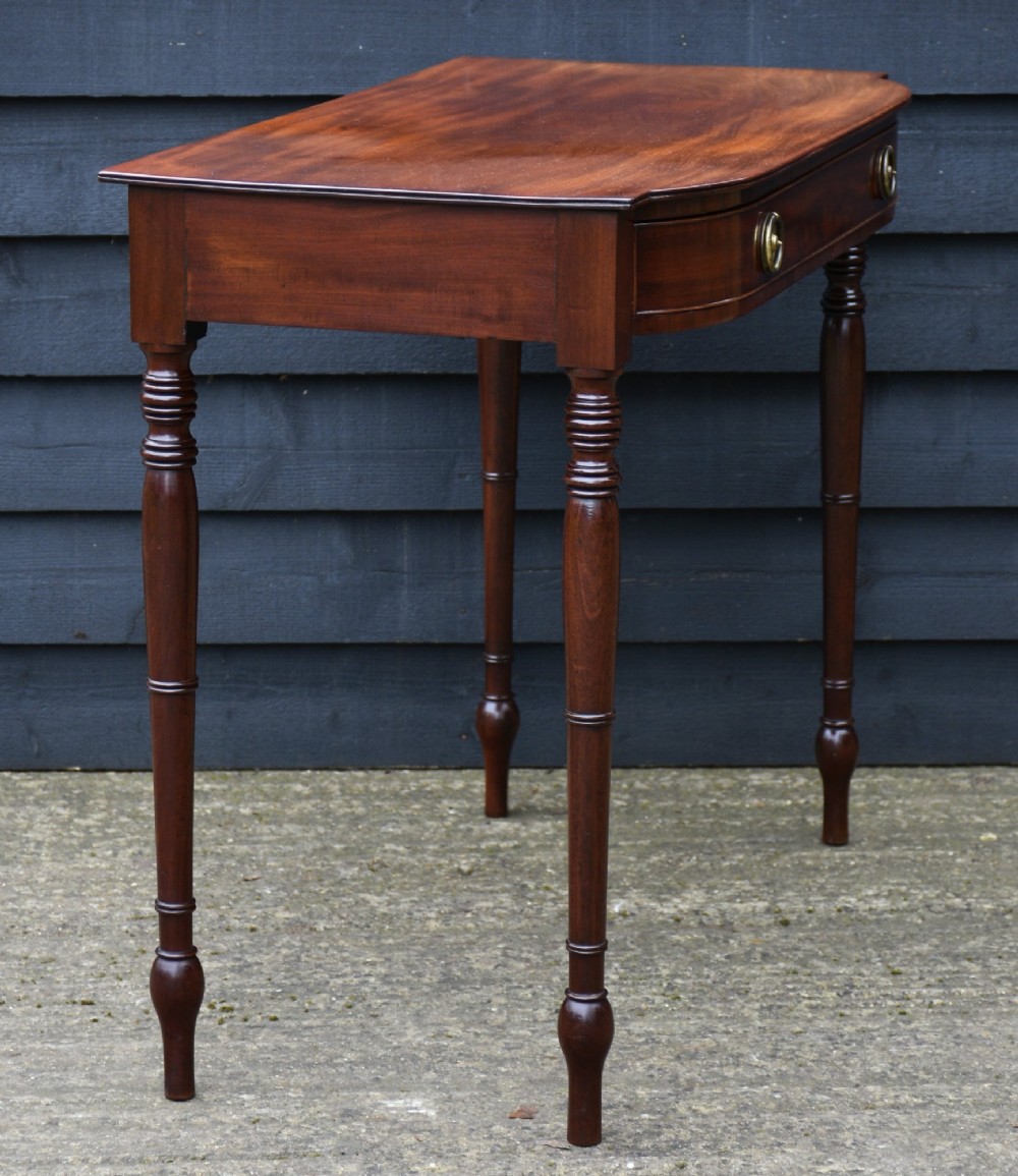 A Regency mahogany bow-fronted side table featuring a central drawer with circular brass handles and slender turned legs. View IV