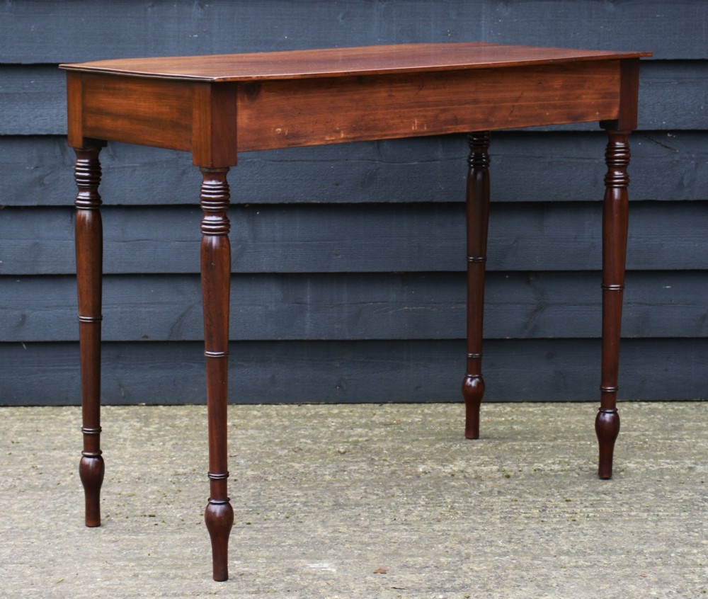 A Regency mahogany bow-fronted side table featuring a central drawer with circular brass handles and slender turned legs. View VI