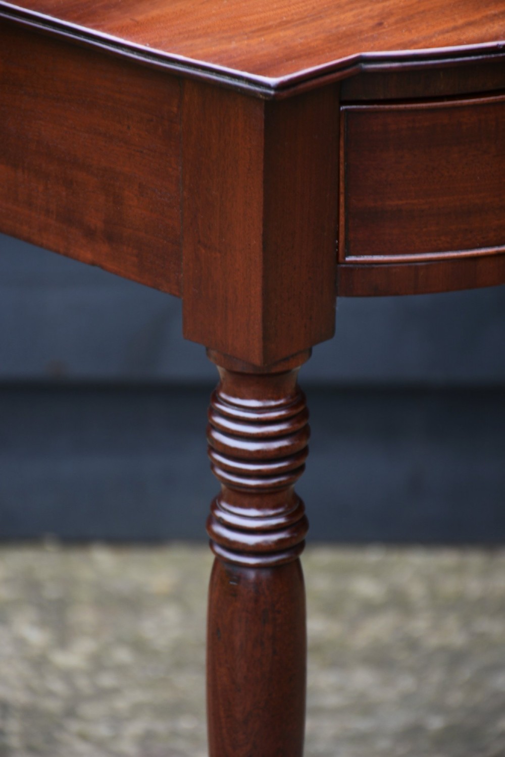 A Regency mahogany bow-fronted side table featuring a central drawer with circular brass handles and slender turned legs. View VIII