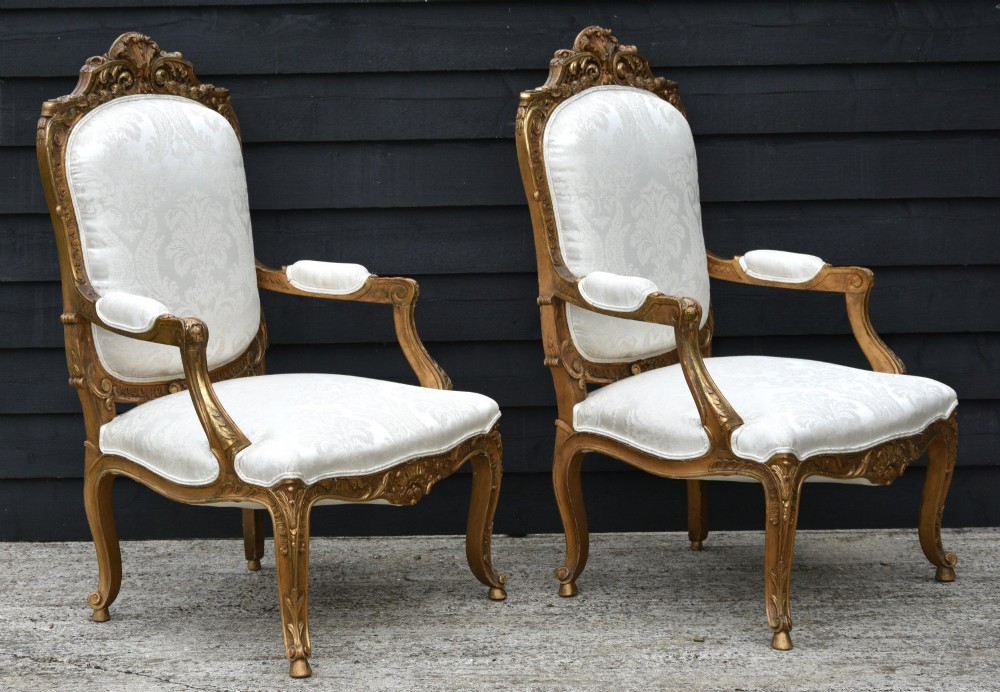 Pair of late 19th-century French giltwood armchairs upholstered in cream damask with carved cresting and cabriole legs. View II