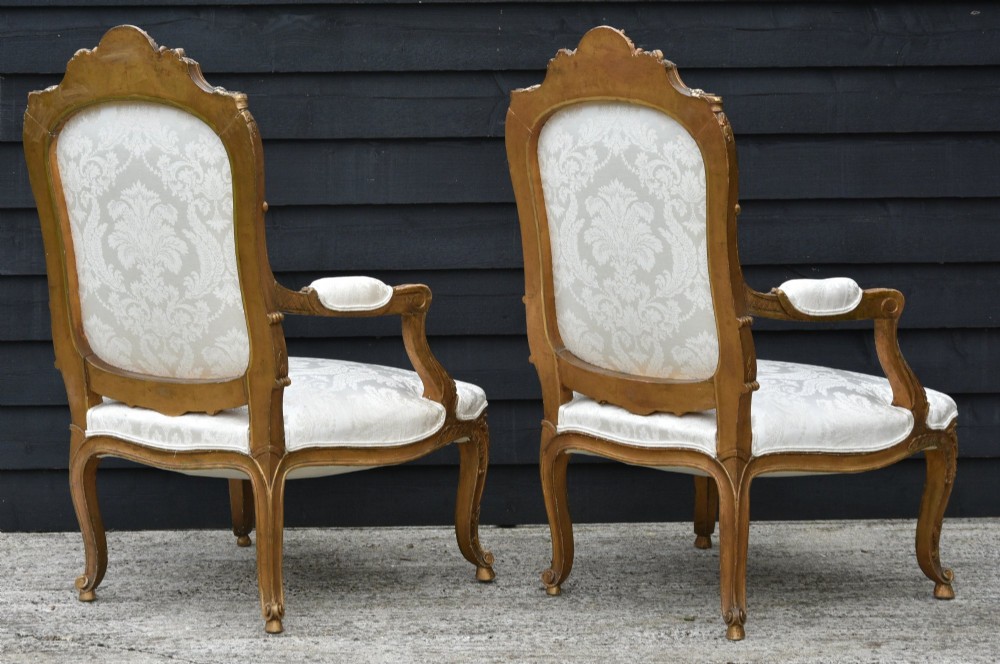 Pair of late 19th-century French giltwood armchairs upholstered in cream damask with carved cresting and cabriole legs. View III