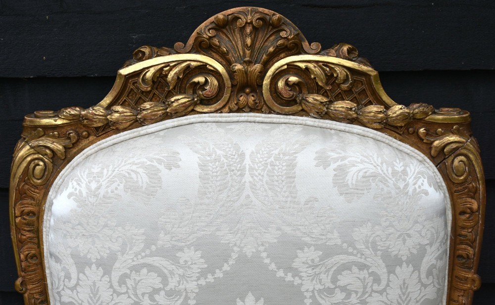 Pair of late 19th-century French giltwood armchairs upholstered in cream damask with carved cresting and cabriole legs. View IV