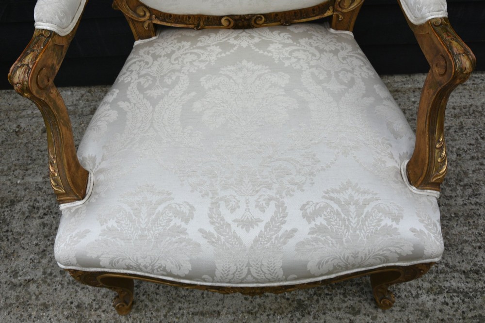 Pair of late 19th-century French giltwood armchairs upholstered in cream damask with carved cresting and cabriole legs. View VIII