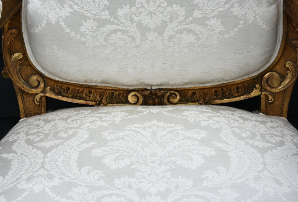 Pair of late 19th-century French giltwood armchairs upholstered in cream damask with carved cresting and cabriole legs. View X