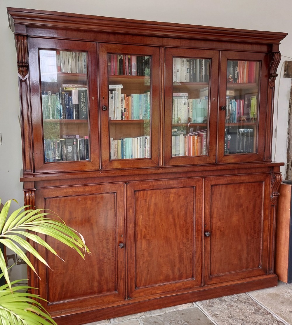 A large William IV mahogany triple bookcase cabinet featuring four upper glazed doors and three lower solid panelled doors.