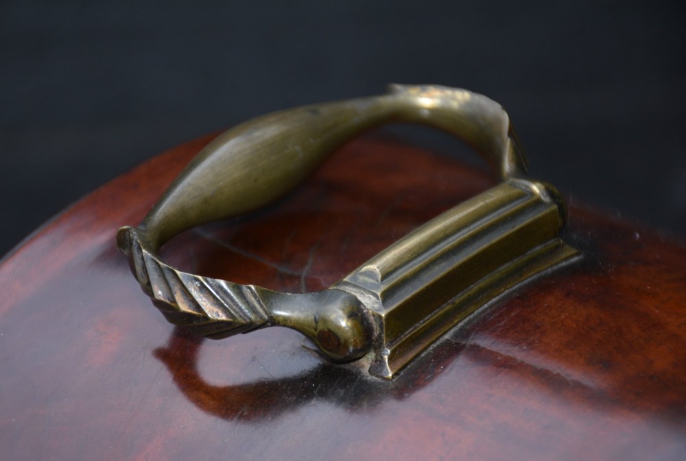 A Georgian mahogany bracket clock featuring an arched top case, top brass carrying handle, pierced side fretwork, engraved dial with Roman numerals, and brass bracket feet. View IV