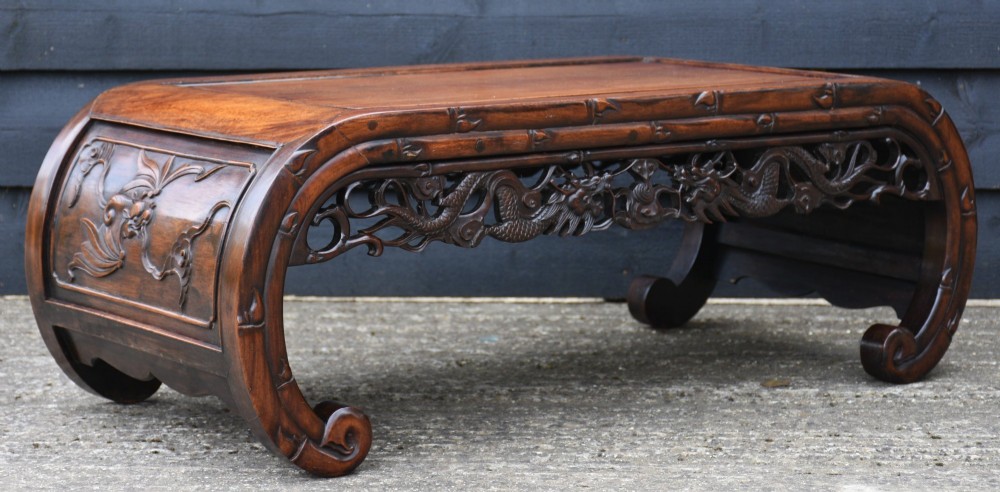 A low Chinese rosewood table with relief-carved dragon aprons, simulated bamboo moulding, and inward-curving scroll feet. View IV