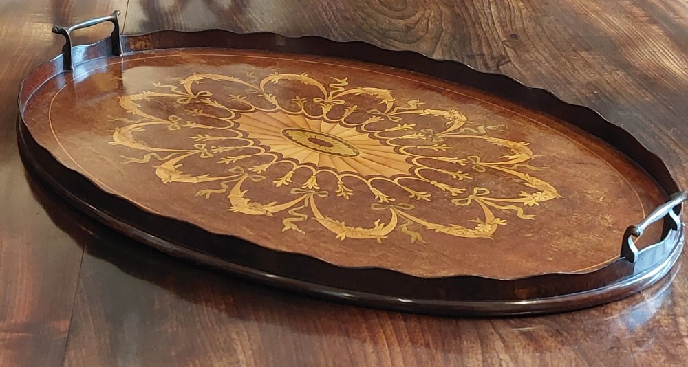 An oval mahogany serving tray featuring intricate central floral marquetry inlay, ribbon swags, and two cast brass side handles. View II