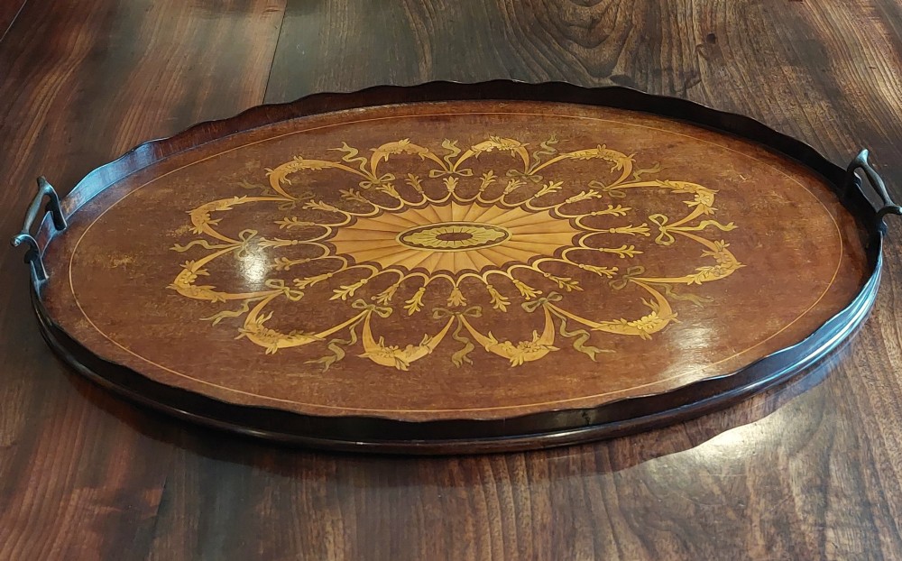 An oval mahogany serving tray featuring intricate central floral marquetry inlay, ribbon swags, and two cast brass side handles. View III